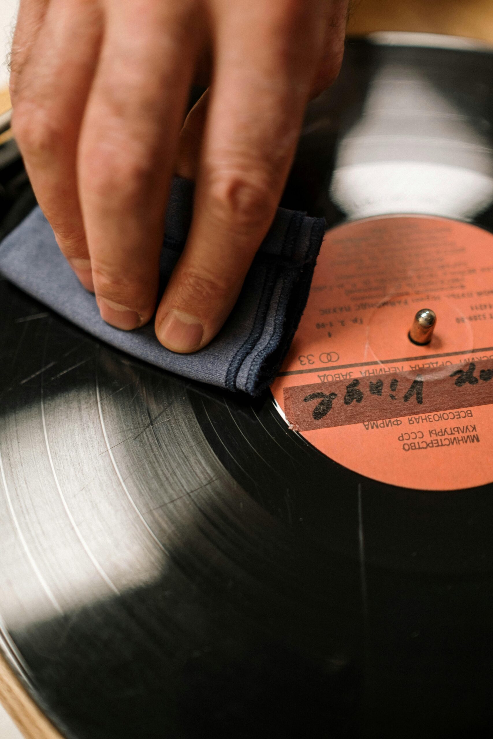 A person cleaning their vinyl record with a microfiber cloth